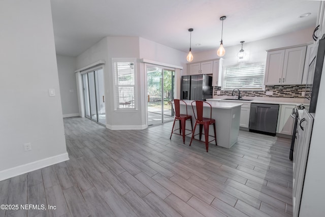 kitchen featuring appliances with stainless steel finishes, backsplash, sink, a kitchen island, and hanging light fixtures