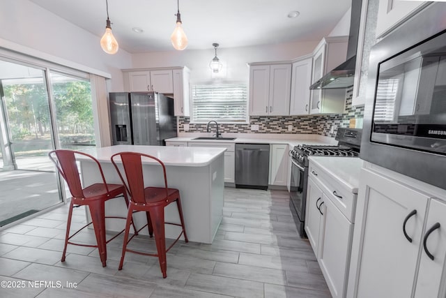 kitchen with stainless steel appliances, sink, a center island, white cabinetry, and hanging light fixtures