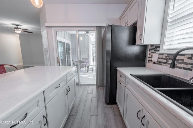 kitchen with backsplash, ceiling fan, white cabinetry, and sink