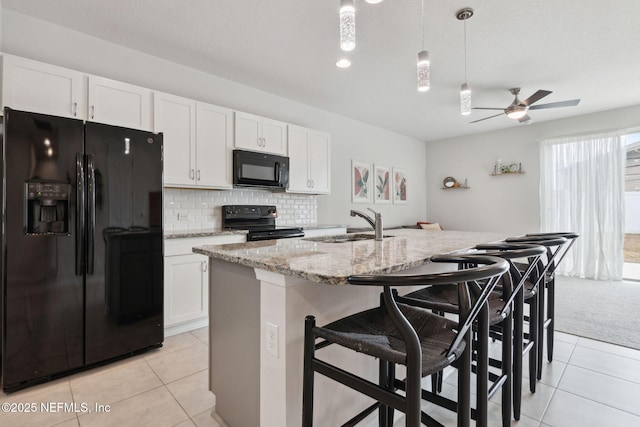 kitchen featuring black appliances, white cabinetry, and a kitchen island with sink