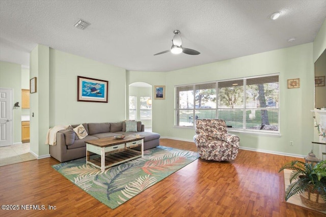 living room with a textured ceiling, light hardwood / wood-style flooring, and ceiling fan