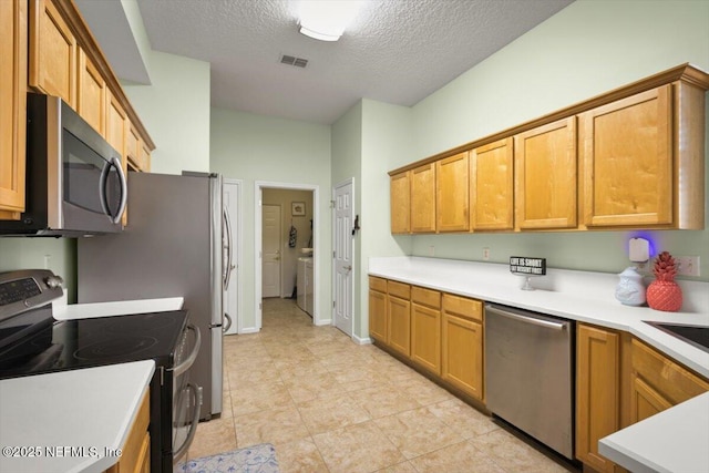 kitchen with stainless steel appliances, washer / clothes dryer, and a textured ceiling