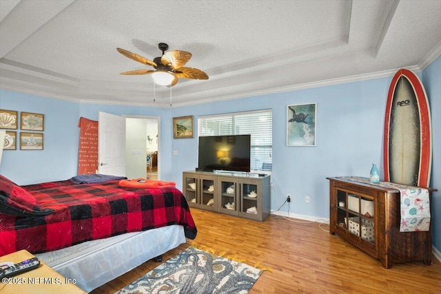 bedroom with hardwood / wood-style flooring, crown molding, a raised ceiling, and a textured ceiling