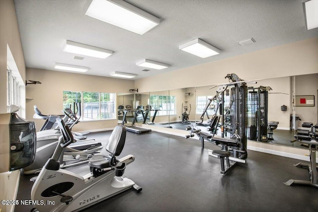 exercise room with visible vents, a textured ceiling, and baseboards