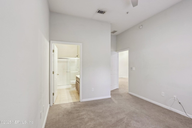 unfurnished bedroom featuring baseboards, visible vents, connected bathroom, and light colored carpet