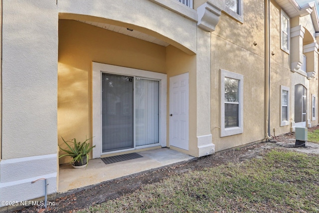 doorway to property featuring stucco siding