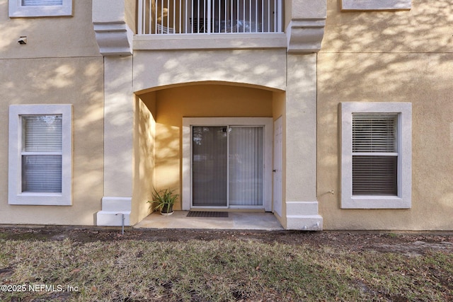 doorway to property with a balcony and stucco siding