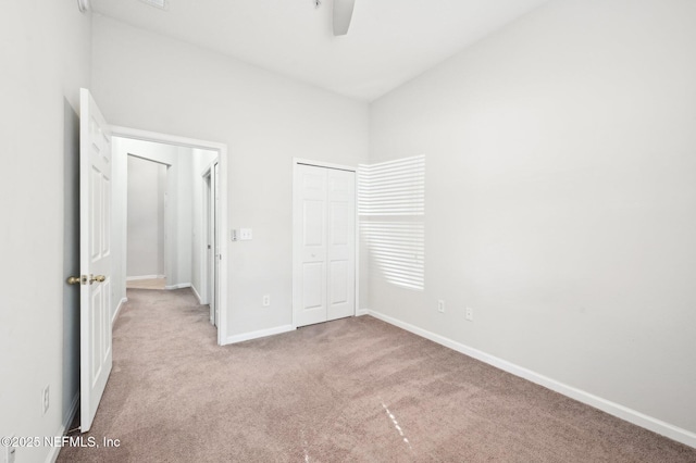 unfurnished bedroom with a closet, carpet, a ceiling fan, and baseboards