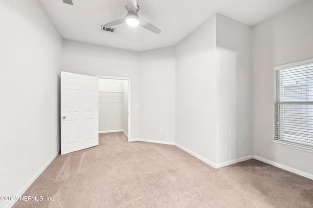 unfurnished room with a ceiling fan, visible vents, light carpet, and baseboards