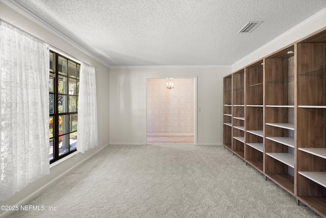 carpeted empty room with a notable chandelier, ornamental molding, and a textured ceiling