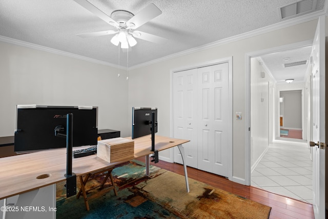 office with ceiling fan, light hardwood / wood-style floors, a textured ceiling, and ornamental molding