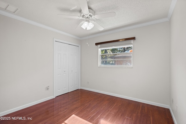 unfurnished bedroom featuring dark hardwood / wood-style flooring, a textured ceiling, ceiling fan, crown molding, and a closet