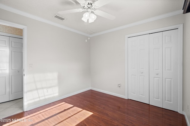 unfurnished bedroom featuring ceiling fan, a closet, hardwood / wood-style flooring, and ornamental molding