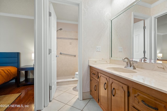 bathroom with tile patterned floors, ornamental molding, a tile shower, vanity, and toilet