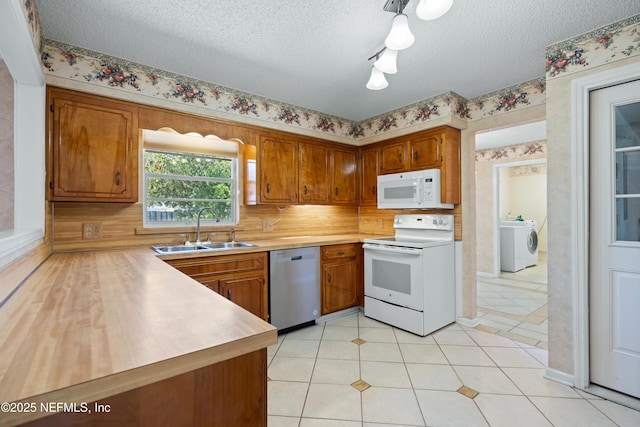 kitchen featuring a textured ceiling, washer / dryer, white appliances, and sink