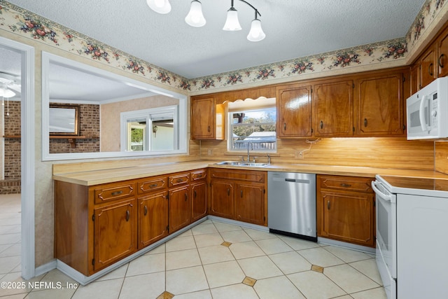 kitchen featuring sink, brick wall, a textured ceiling, decorative light fixtures, and white appliances