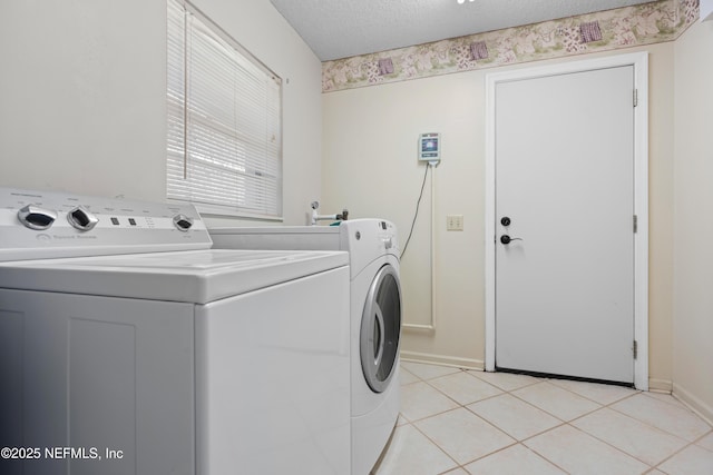 washroom featuring washer and dryer, light tile patterned floors, and a textured ceiling