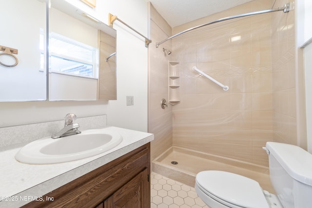 bathroom featuring toilet, tile patterned floors, tiled shower, and vanity