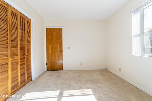 unfurnished bedroom featuring light colored carpet and a closet