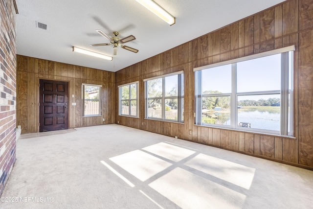 unfurnished sunroom with ceiling fan and a water view