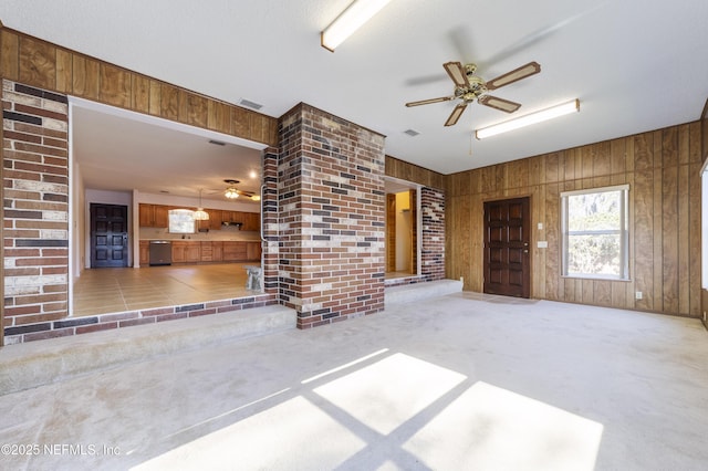 unfurnished living room with ceiling fan, carpet floors, and wooden walls