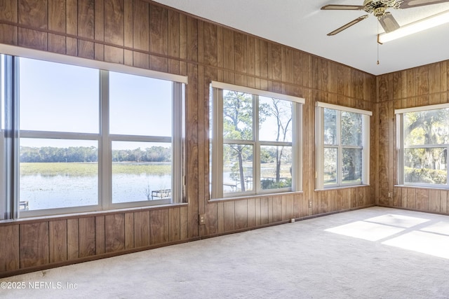 unfurnished sunroom featuring ceiling fan and a water view