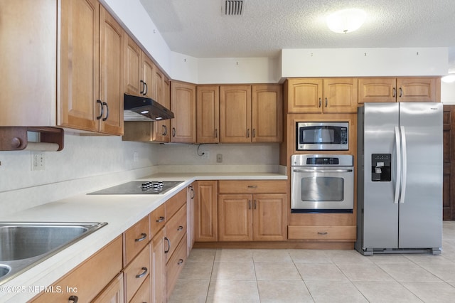 kitchen featuring a textured ceiling, appliances with stainless steel finishes, light tile patterned floors, and sink