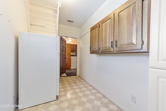 hall featuring a textured ceiling and washer / clothes dryer