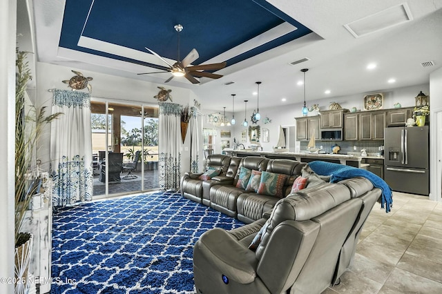 living room with a tray ceiling and ceiling fan