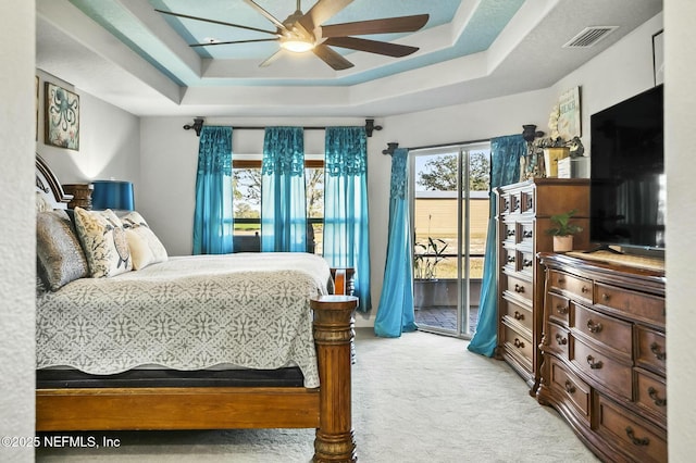 bedroom featuring a raised ceiling, access to exterior, ceiling fan, and light carpet