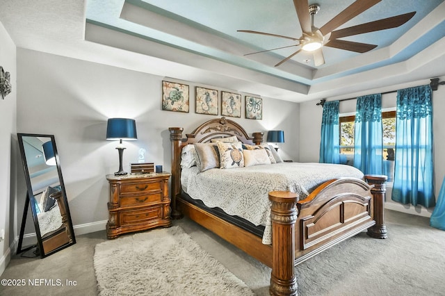 bedroom featuring carpet flooring, a tray ceiling, and ceiling fan