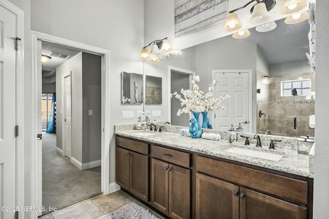 bathroom with tiled shower, vanity, and tile patterned floors