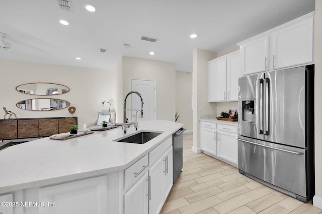 kitchen featuring a kitchen island with sink, appliances with stainless steel finishes, sink, and white cabinets