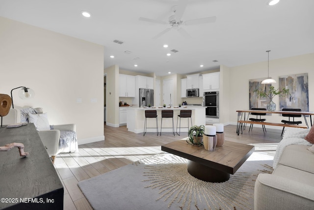 living room with ceiling fan and light wood-type flooring