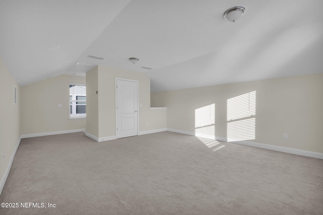 additional living space featuring lofted ceiling and light carpet