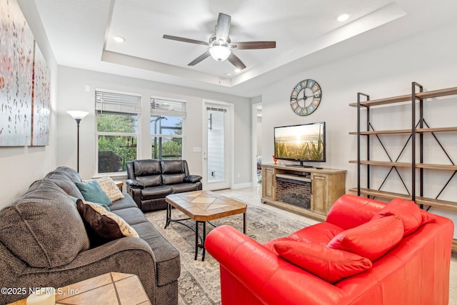 tiled living room with a raised ceiling and ceiling fan