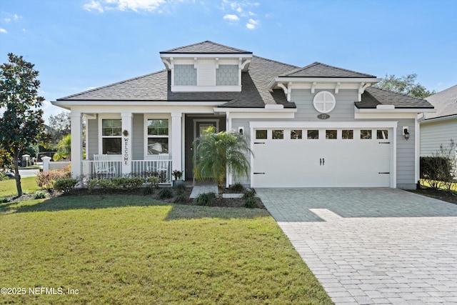 view of front of property featuring a front yard, a porch, and a garage