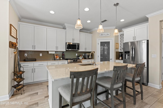 kitchen with sink, white cabinetry, stainless steel appliances, and an island with sink