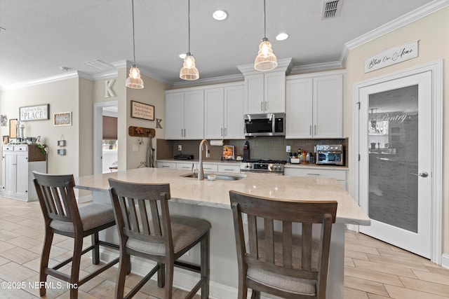 kitchen with white cabinetry, sink, an island with sink, decorative light fixtures, and appliances with stainless steel finishes