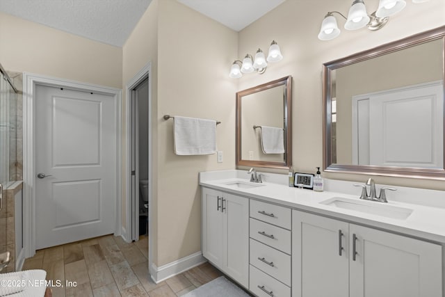 bathroom featuring vanity, toilet, a shower with door, and a textured ceiling