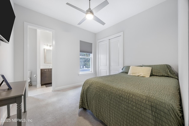 carpeted bedroom featuring a closet, ensuite bath, and ceiling fan