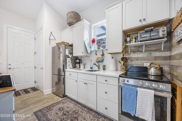 kitchen featuring sink, backsplash, white cabinets, light hardwood / wood-style floors, and stainless steel appliances