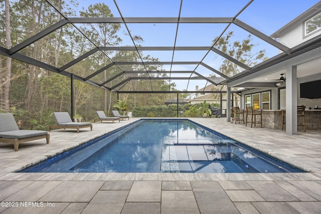 view of swimming pool with glass enclosure, an outdoor bar, ceiling fan, a jacuzzi, and a patio