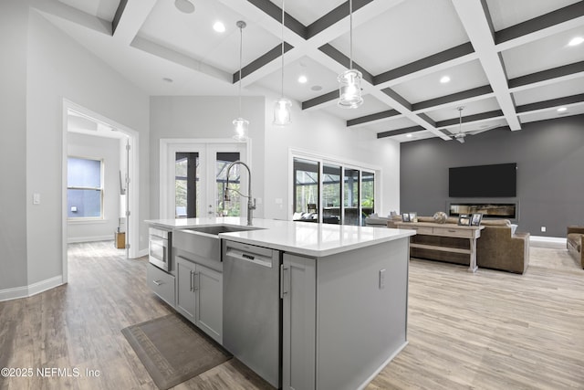 kitchen with decorative light fixtures, stainless steel appliances, an island with sink, gray cabinets, and ceiling fan