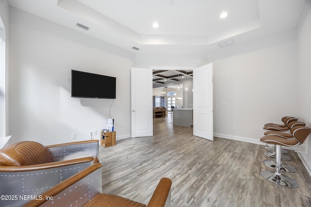 sitting room with wood-type flooring and a tray ceiling