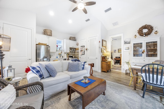 living room with lofted ceiling, light wood-type flooring, and ceiling fan