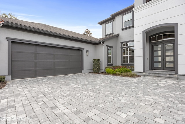 view of exterior entry with a garage and french doors