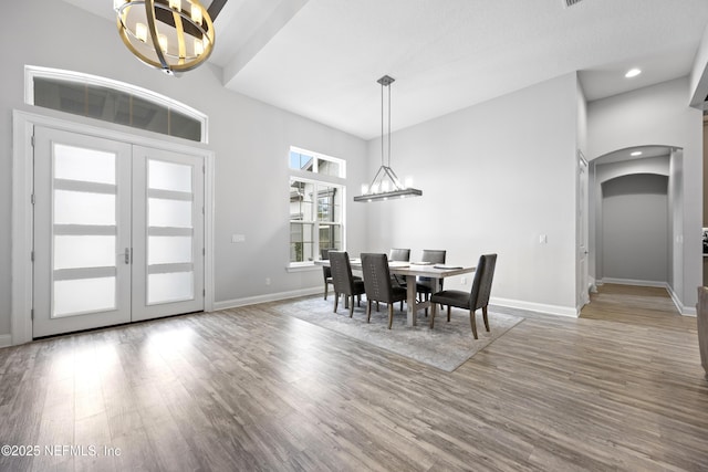 dining space featuring wood-type flooring, an inviting chandelier, and a towering ceiling