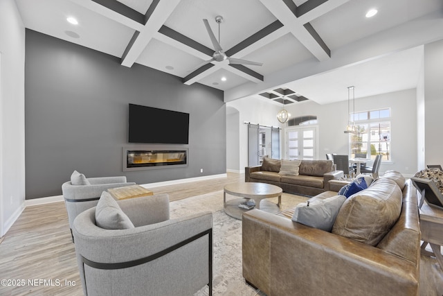 living room with coffered ceiling, beamed ceiling, ceiling fan with notable chandelier, and light hardwood / wood-style floors