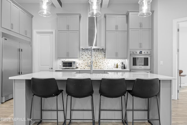 kitchen with a kitchen breakfast bar, appliances with stainless steel finishes, a kitchen island with sink, and tasteful backsplash